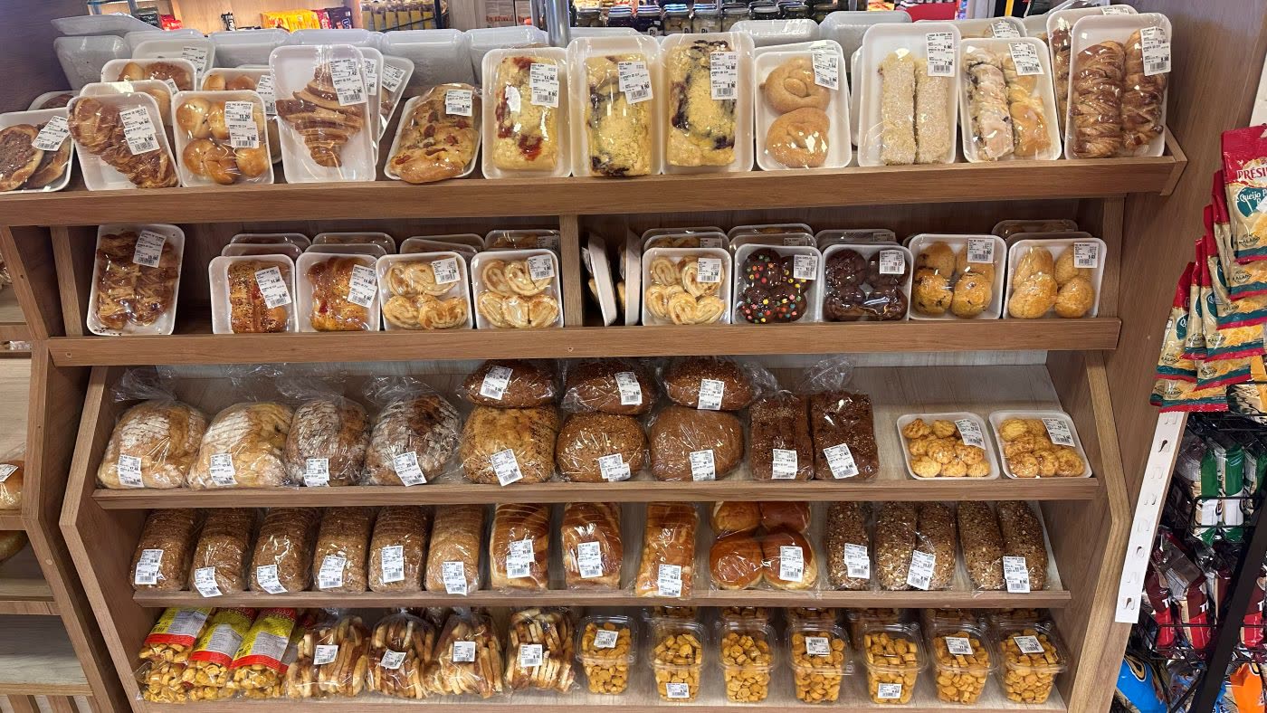 Estante com croissants, folhados, cucas, biscoitos e pães artesanais embalados
