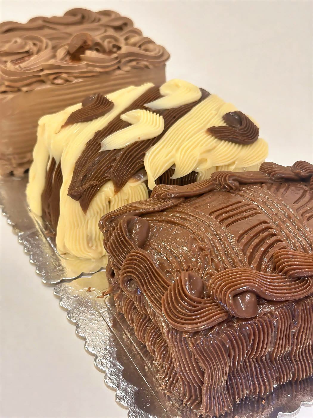 Bolos gelados decorados com coberturas de chocolate, doce de leite e mesclada