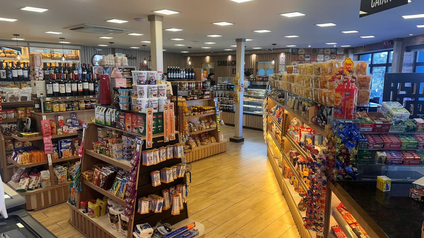 Interior da loja com gôndolas de produtos, adega e corredor do caixa